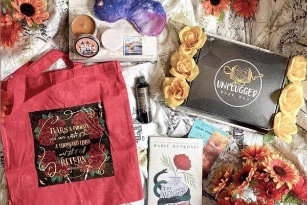 an unplugged box with various items such as candles, a sleep mask, and a novel