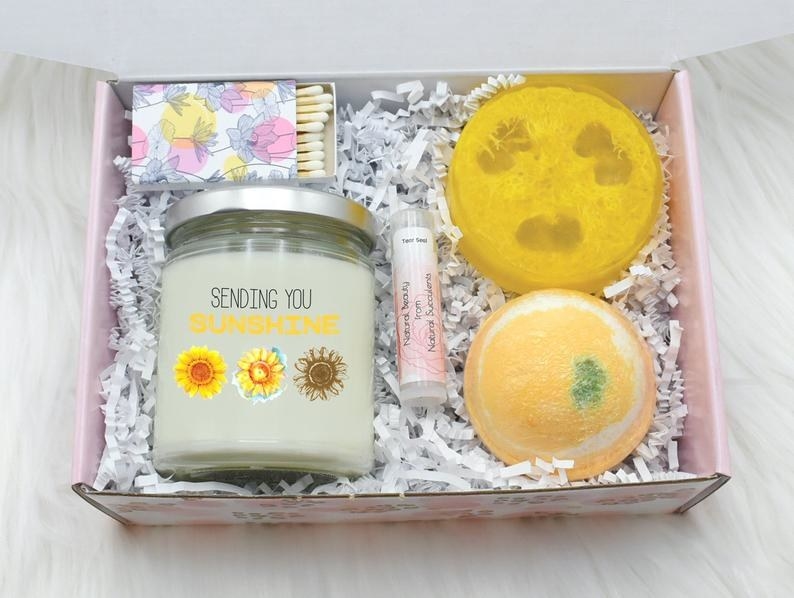 a candle, loofah, bath bomb, and box of matches in the box