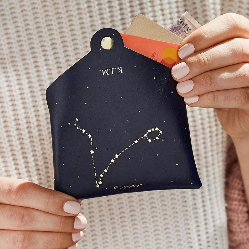 a model holding the coin purse with a constellation on it
