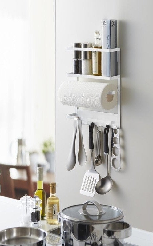 A hanging kitchen rack inside a kitchen holding cooking utensils next to a stove