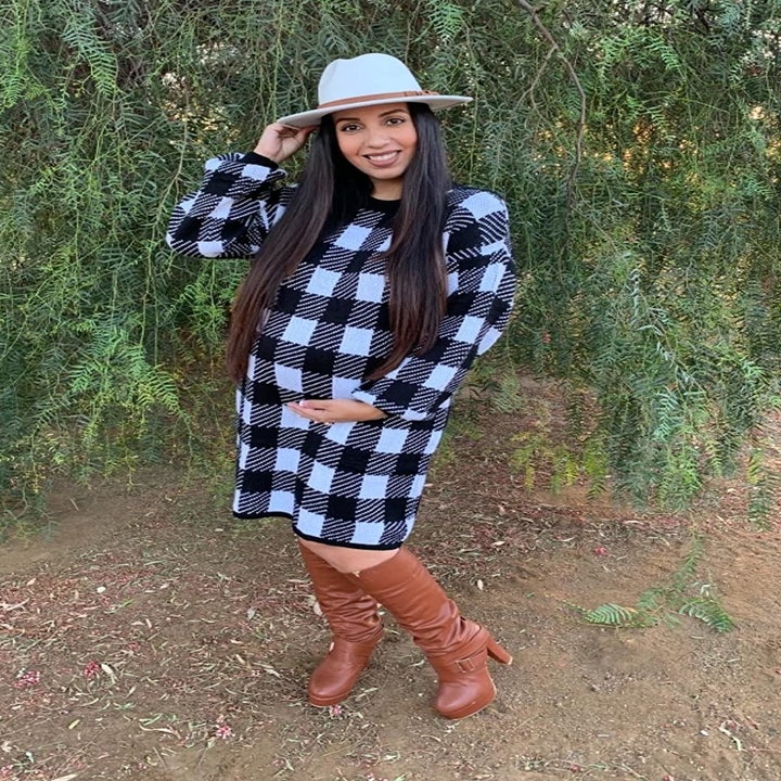 A reviewer wearing the knee-length sweater dress in black and white plaid 