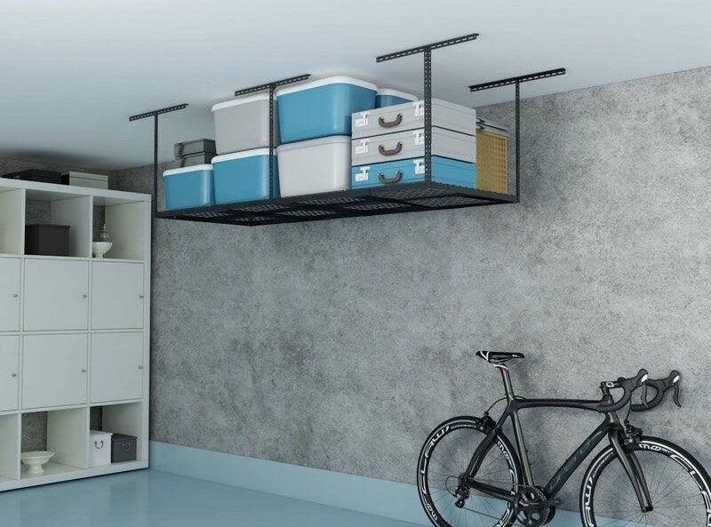 A very clean garage with an overhead storage system holding bins and crates