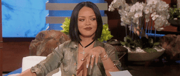 Rihanna winking and gesturing at Ellen DeGeneres. 