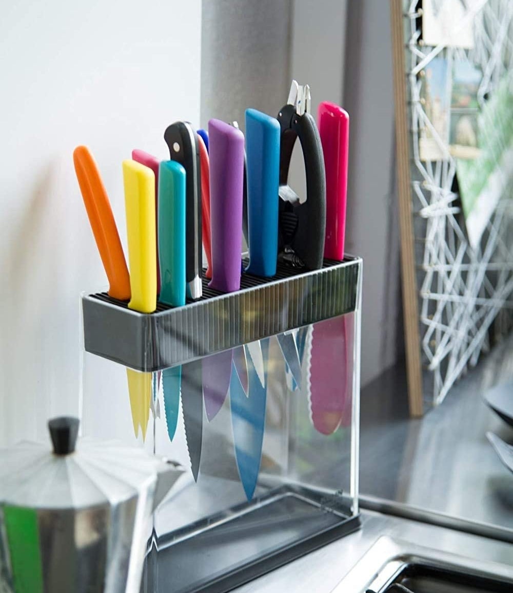 The transparent knife block on a counter filled with blades of different shapes and sizes