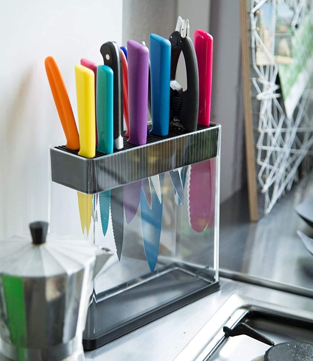 The transparent knife block on a counter filled with blades of different shapes and sizes