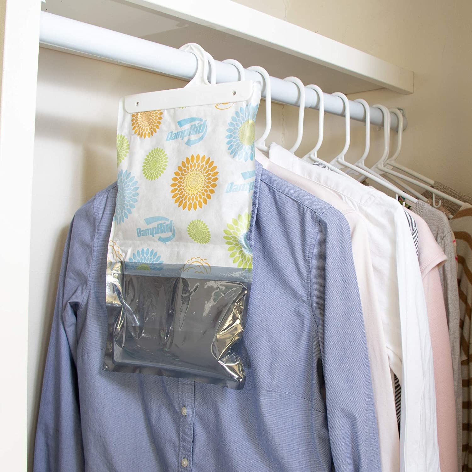 A moisture-absorbing bag hanging on a closet rod in front of shirts