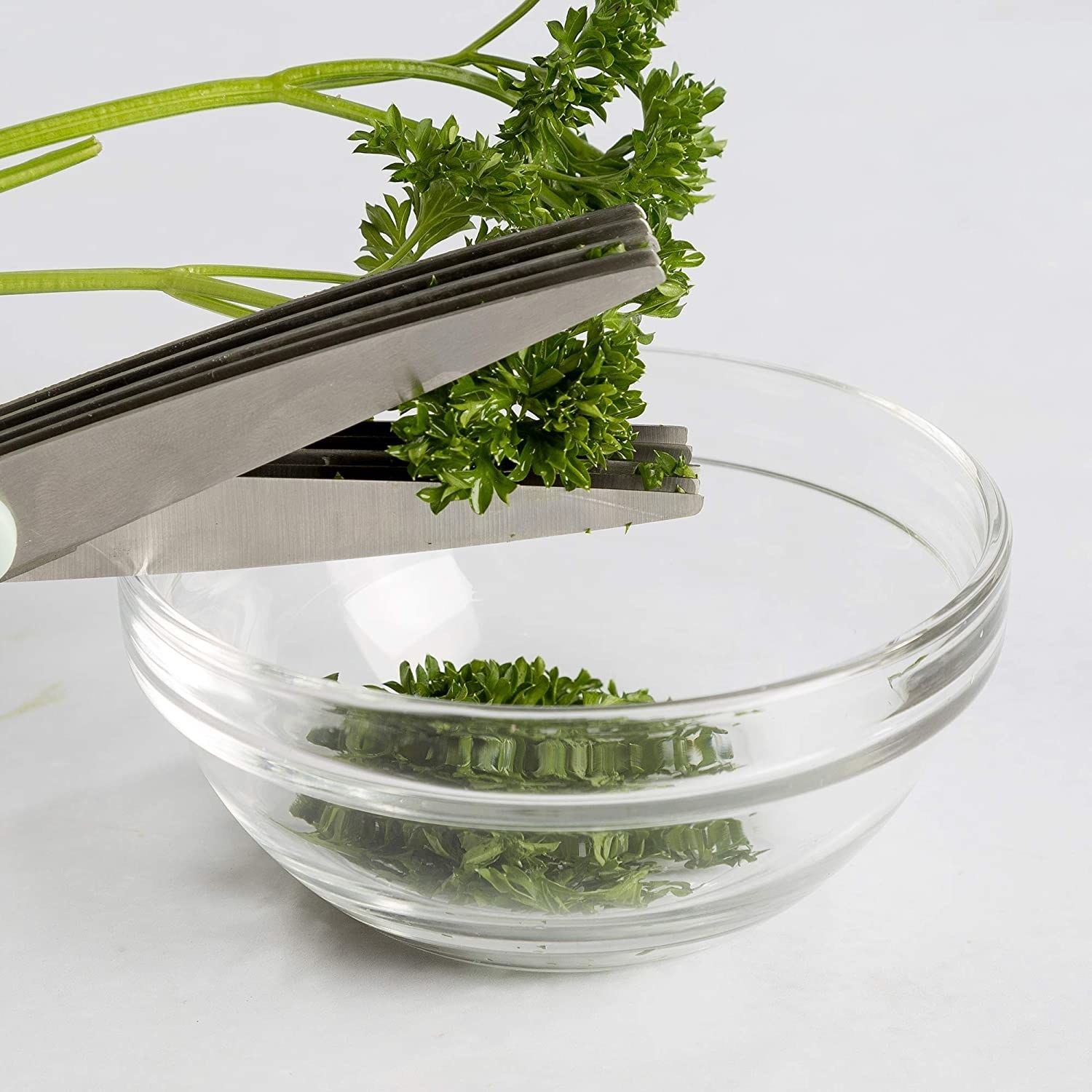 Hands using the scissors to cut herbs into a bowl