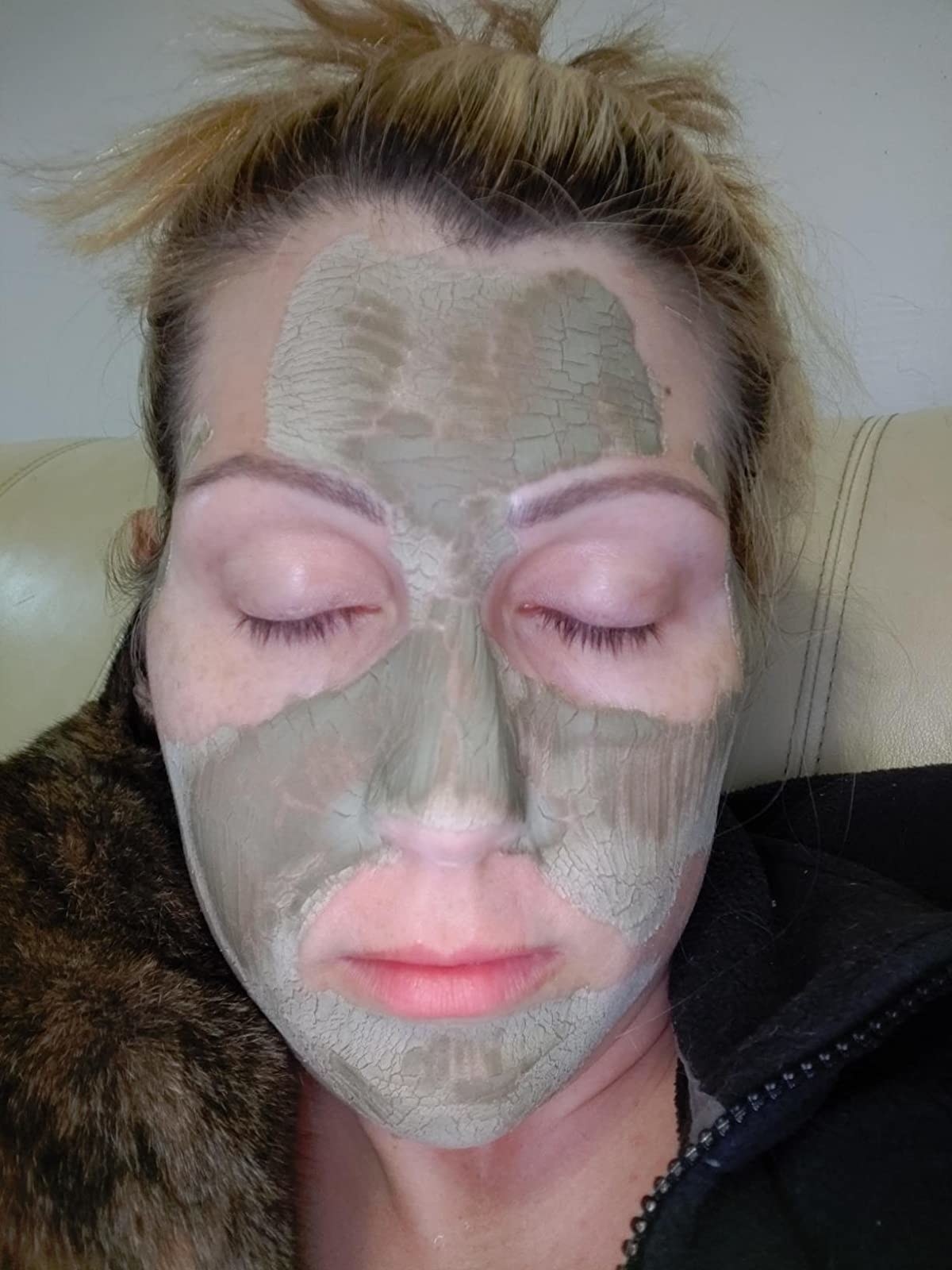 A reviewer with the light green clay mask on their face