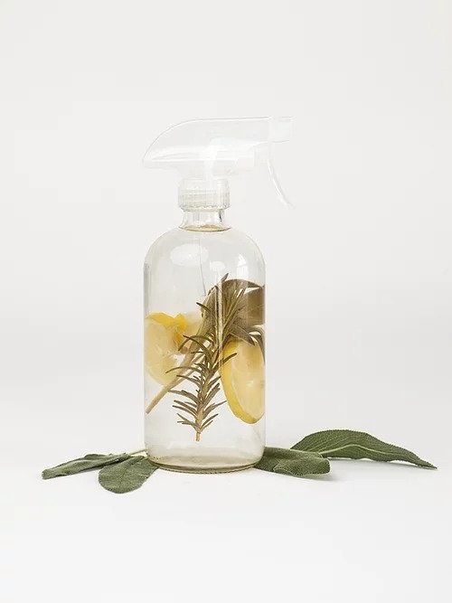 glass spray bottle filled with rosemary, sage, and lemon 