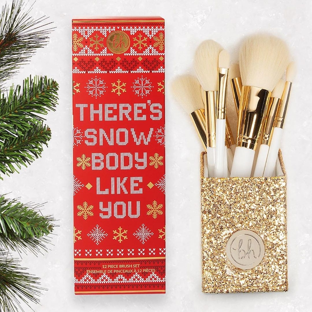 The white brushes in their gold holder, next to the red gift box that says "there's snow body like you"