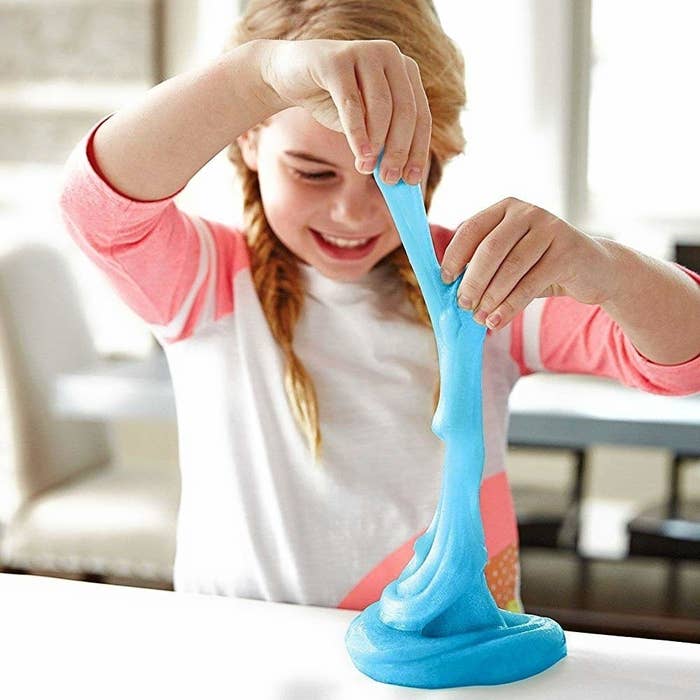 A child plays with blue, stretchy slime that they made with the ingredients in the kit