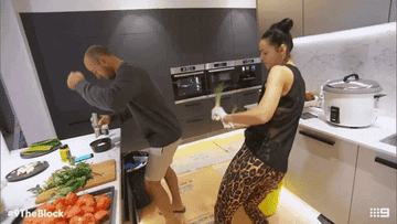 GIF of a man and woman silly-dancing in the kitchen