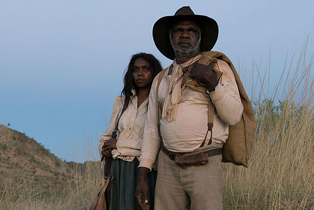 An Aboriginal man and woman looking off into the distance while standing in the Australian bush 