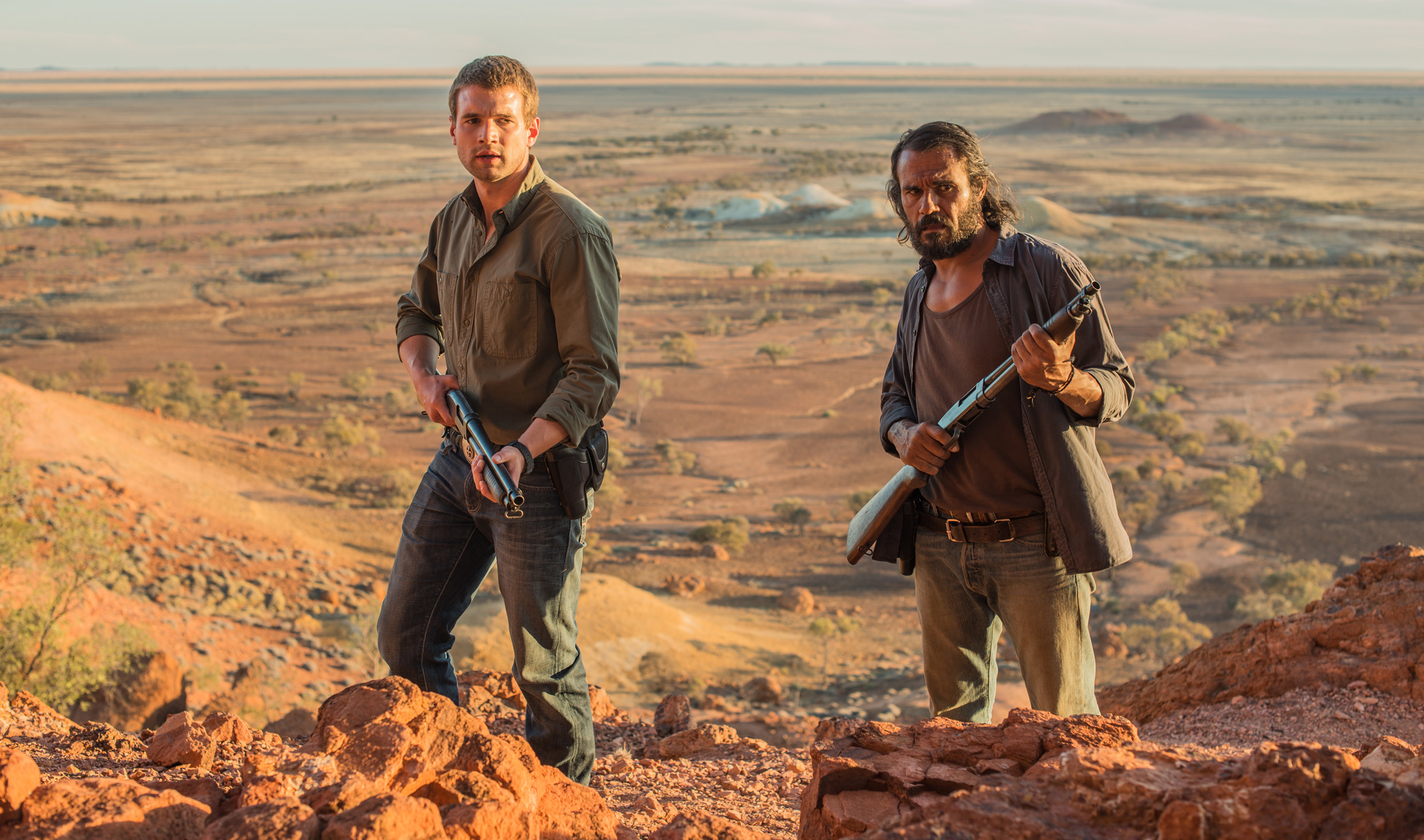 Two men in the Australian outback holding guns