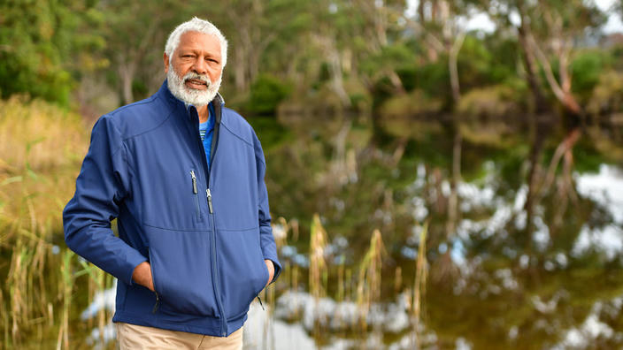Ernie Dingo standing in front of a lake