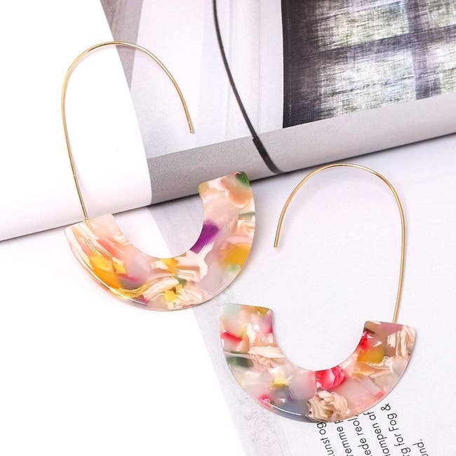 The earrings, with gold wire hooks and half-moon multicolor resin hanging from them