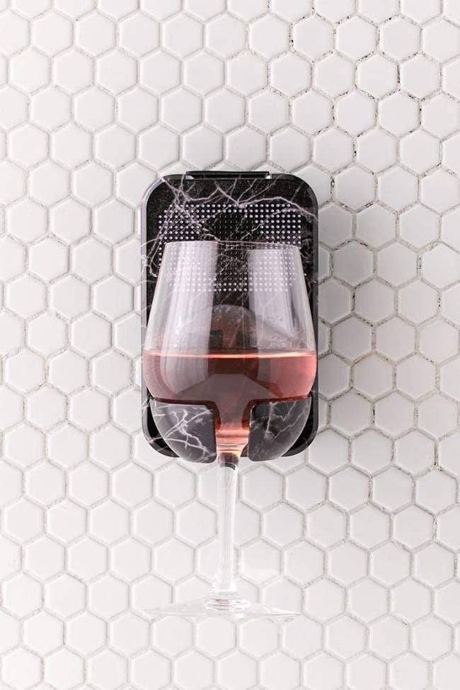The black marble print caddy holding a wine glass on a tile wall