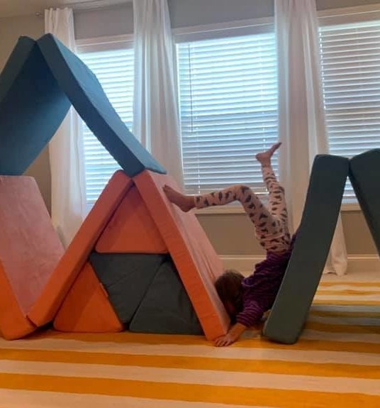 A child playing with Nugget cushions falls down