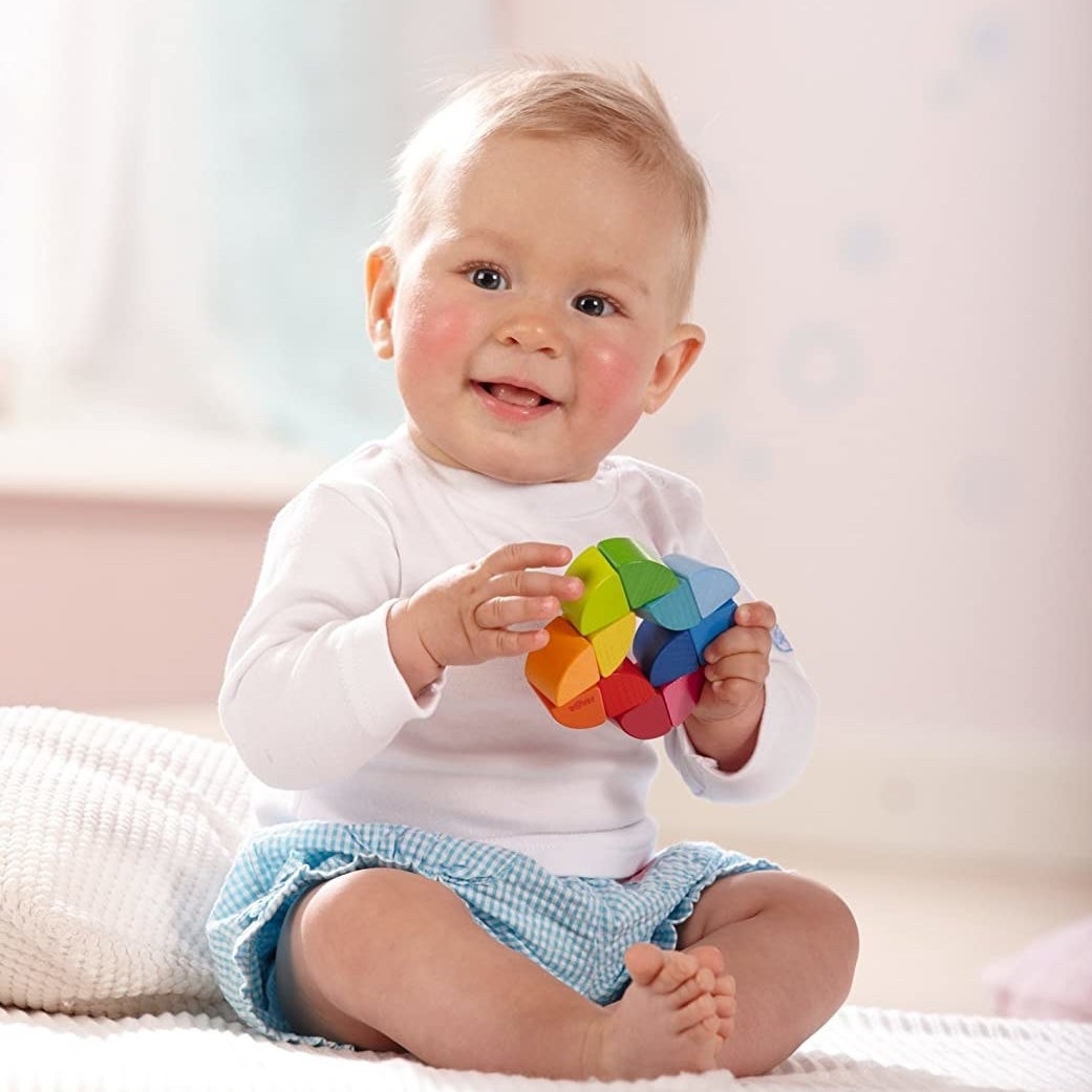 Child model holding multi-colored wooden toy