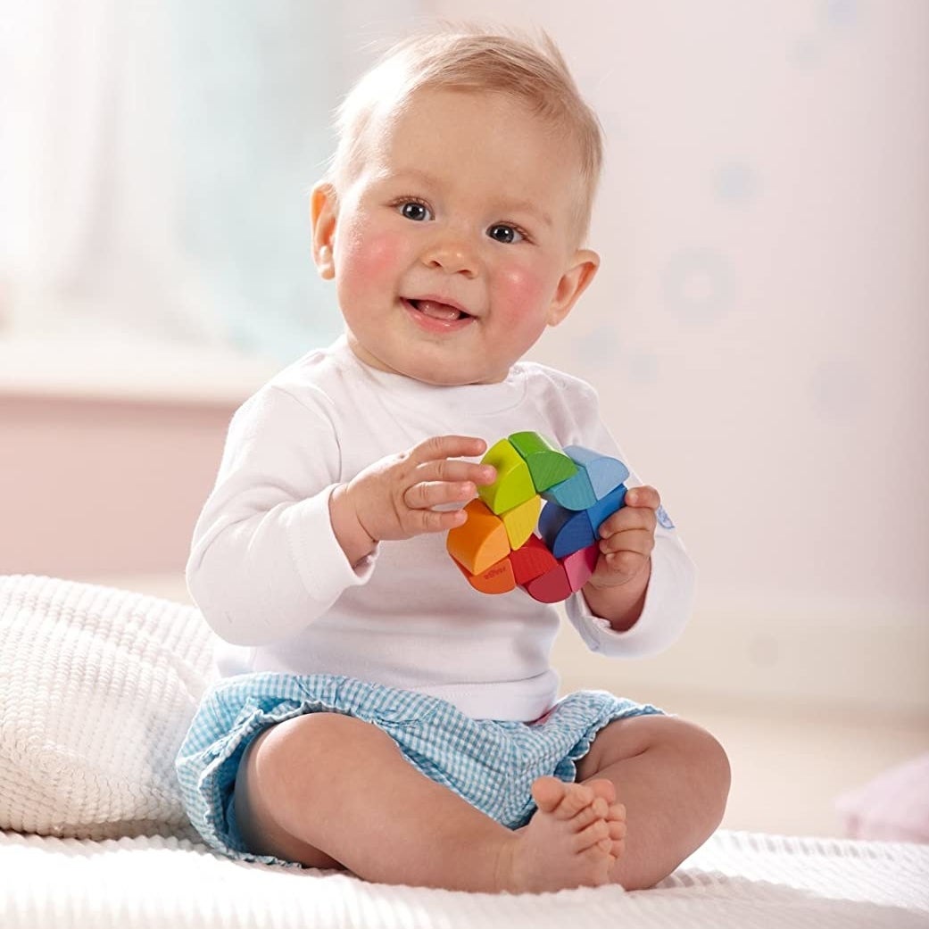 Child model holding multi-colored wooden toy