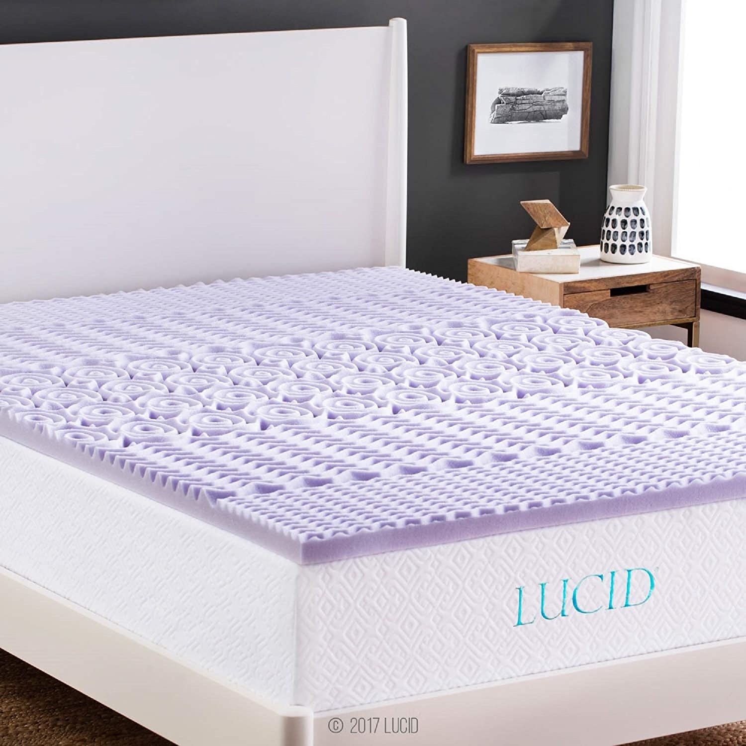 A thin foam mattress topper placed on top of a thick mattress