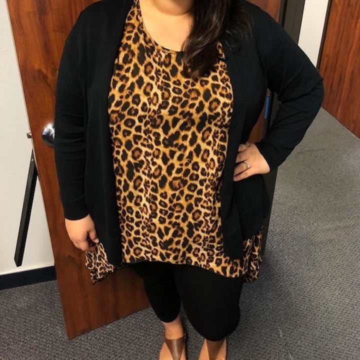 reviewer wearing the cardigan in black with leggings and a leopard print top 