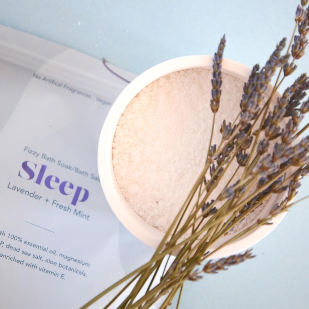 A flatlay of the salts in a container decorated with lavender sprigs