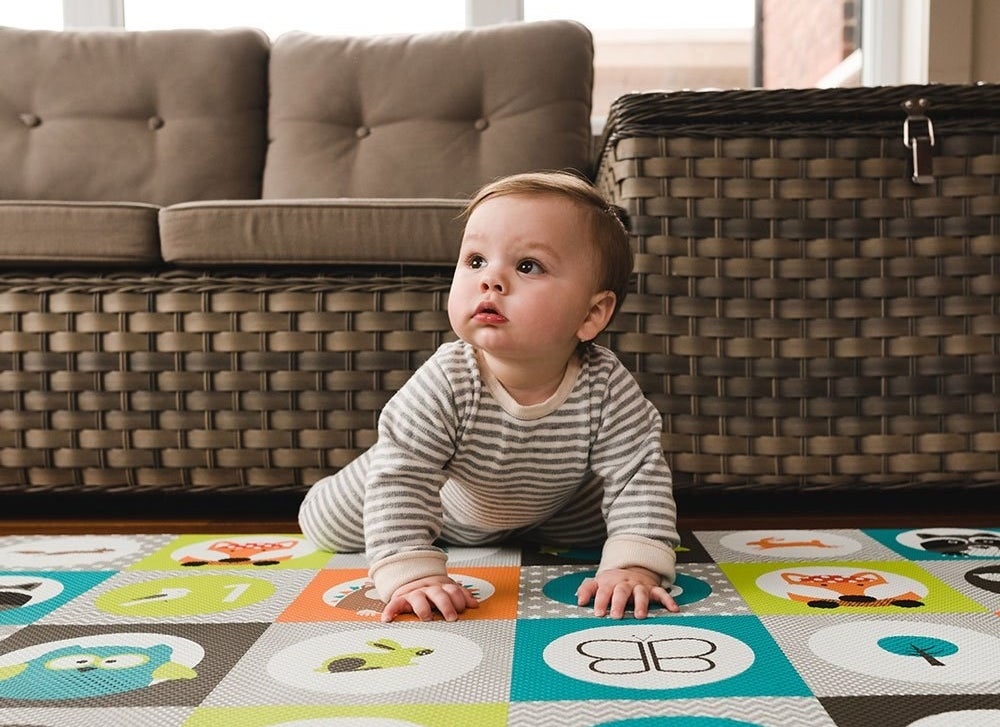 Baby model crawling on a multi-colored play mat