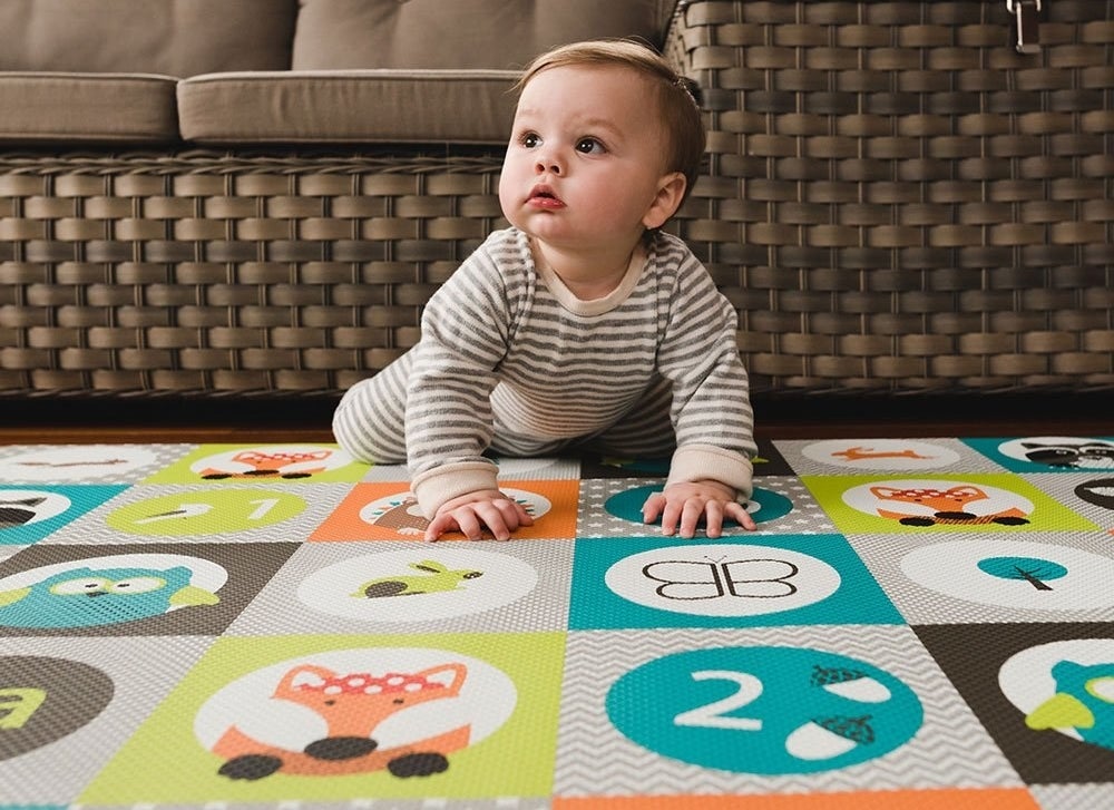 Baby model crawling on a multi-colored play mat