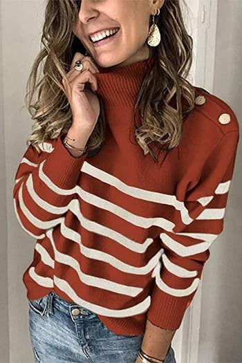 A model wearing the rust and white striped sweater with metallic buttons at the shoulder