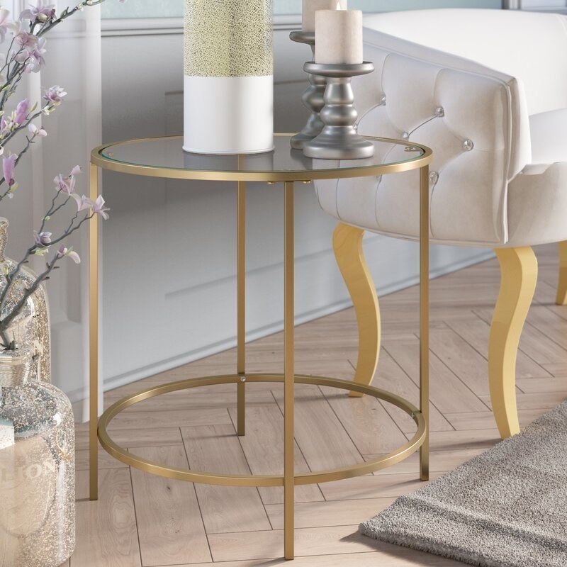 A round end table with glass top and gold frame