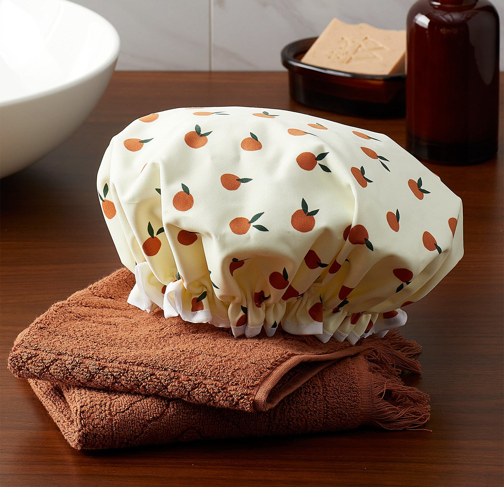 A shower cap with a fruit pattern on it lying on a folded towel
