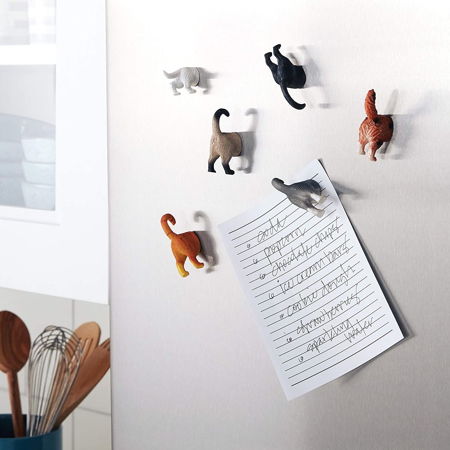 A cat-shaped magnet holding up a sheet of paper on a fridge door