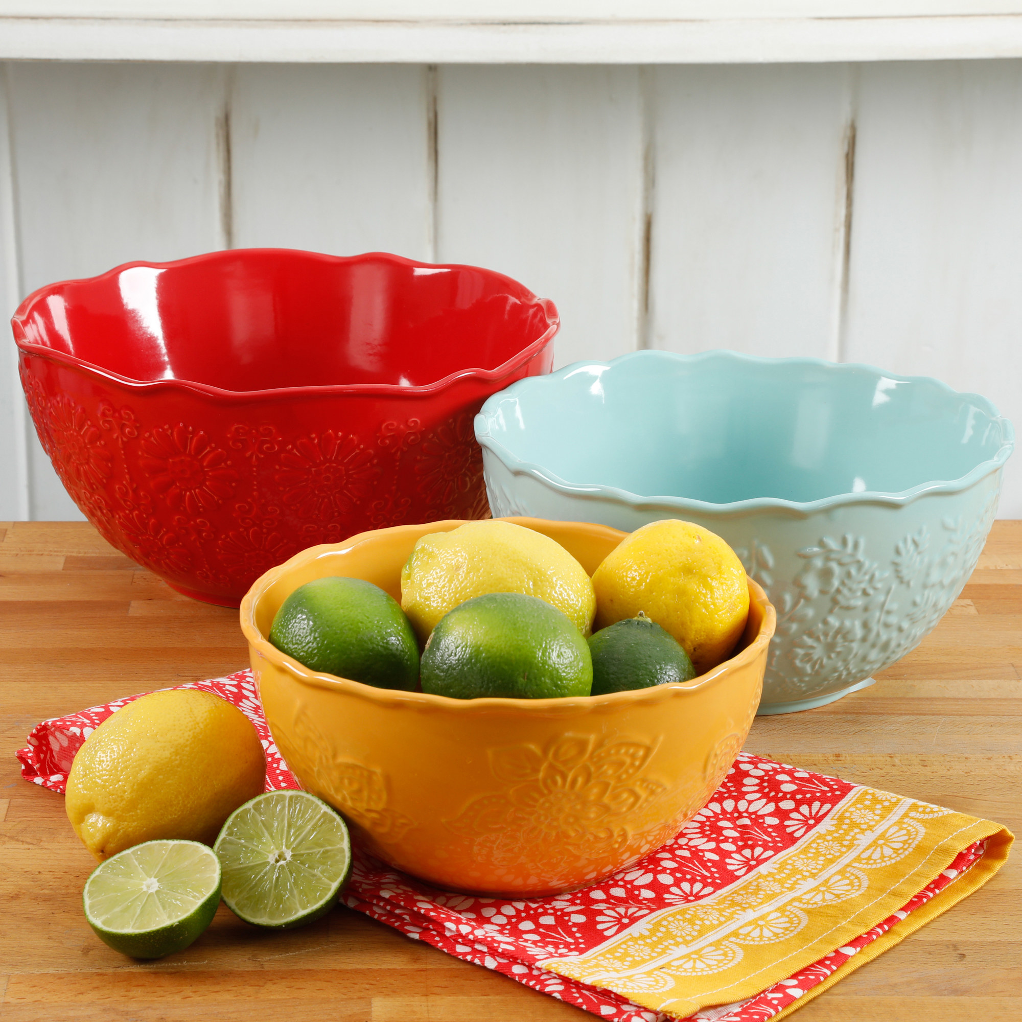 The three serving bowls in red orange and light blue, with one holding limes and lemons to show its size