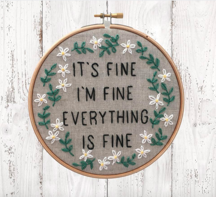 An embroidered circle with the words it's fine, i'm fine, everything is fine stitched on the front
