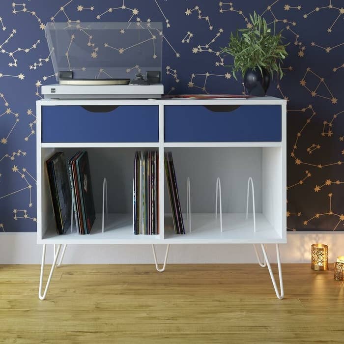 White audio rack with blue drawers, a white and clear record player and a variety of records 