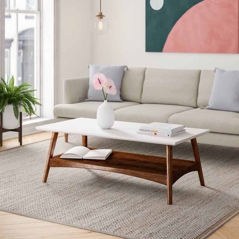 A coffee table with wooden legs and lower tier and white glossy top