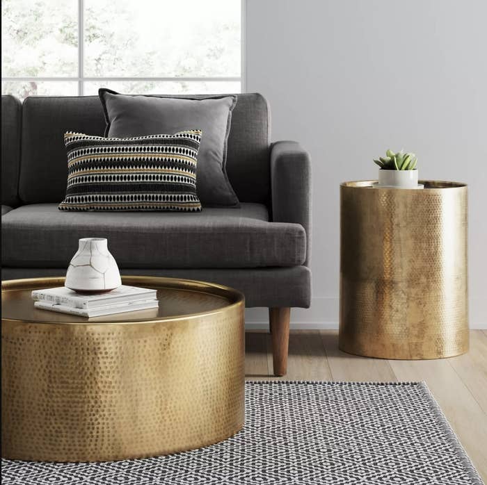 A gold side table next to a couch in a living space