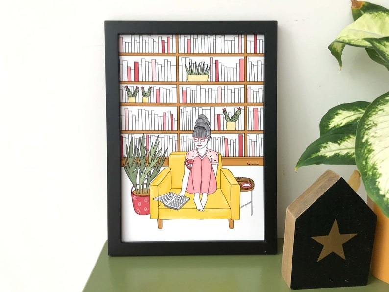 An art print of a person sitting on a couch in their library reading a book