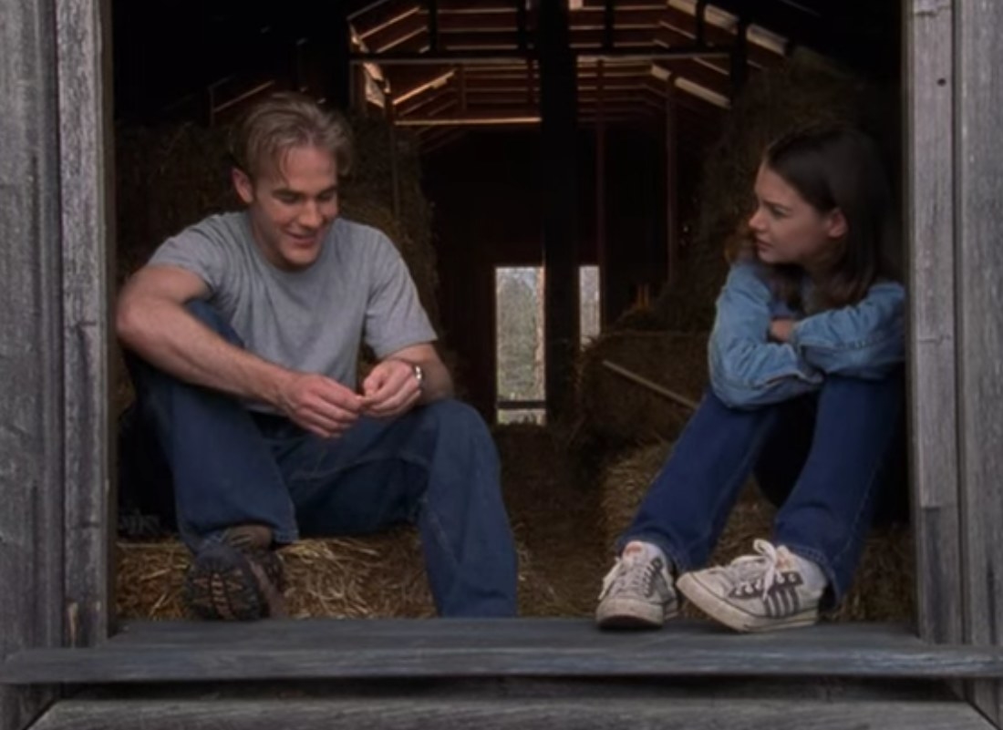 Joey and Dawson talk to each other while sitting on hay in a barn
