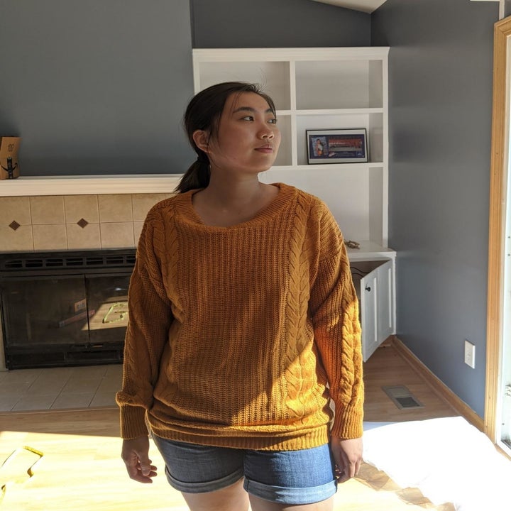 reviewer wearing the sweater in a ginger gold