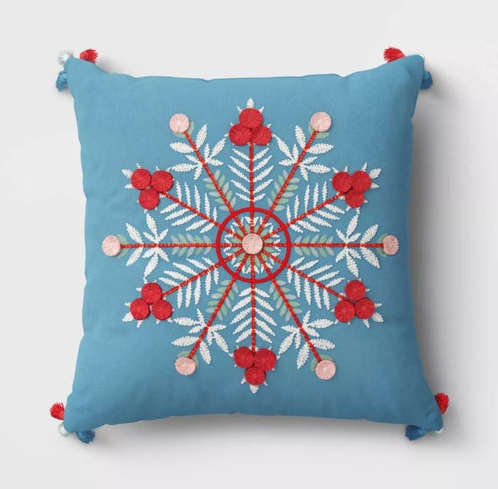 Blue pilow with red white and pink embroidered snowflake/blue, white and red pompoms on corner