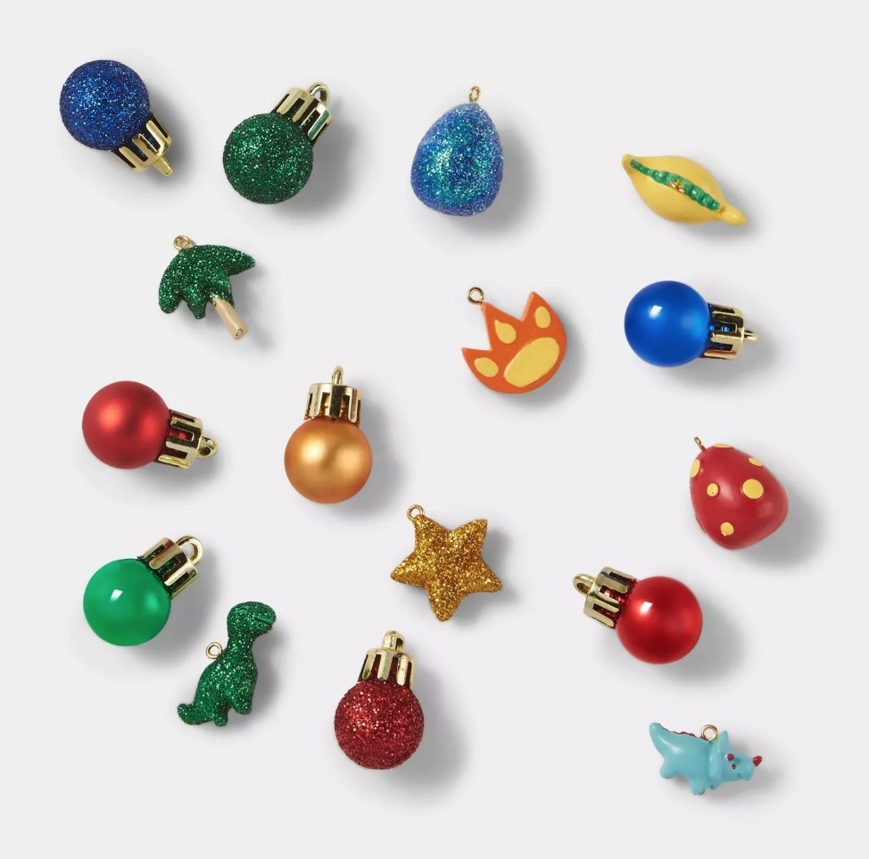 Assorted ornaments—red, green, and blue with dinosaur shaped, tree, dino foot print, and star ornament