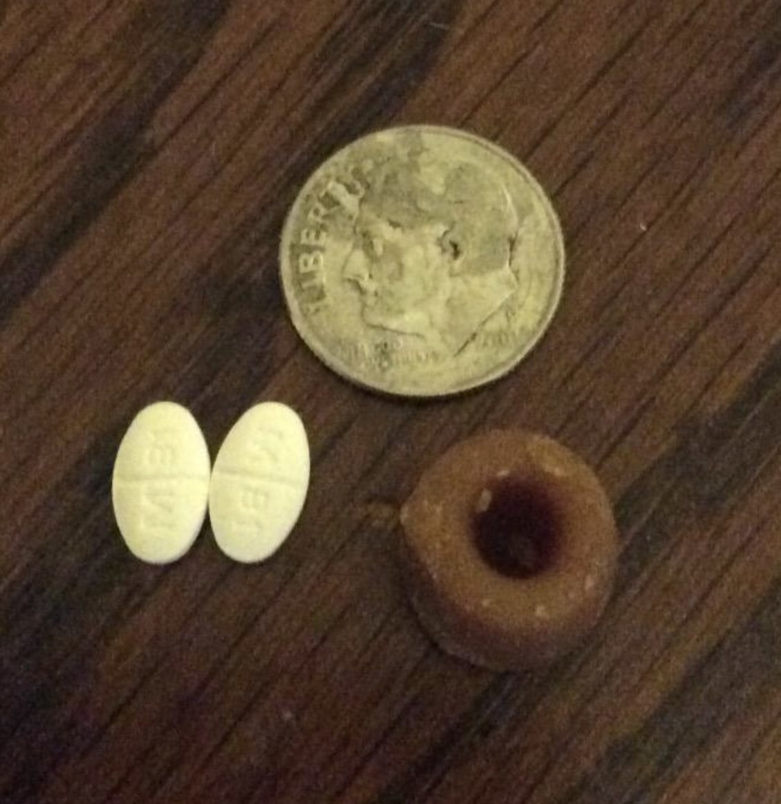 a feline greenies pill pocket next to two pills and a dime for size