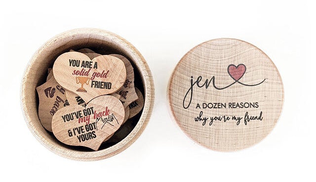 A collection of 12 wooden hearts with different messages on them inside their box with a lid that reads &quot;Jen a dozen reasons why you&#x27;re my friend&quot;