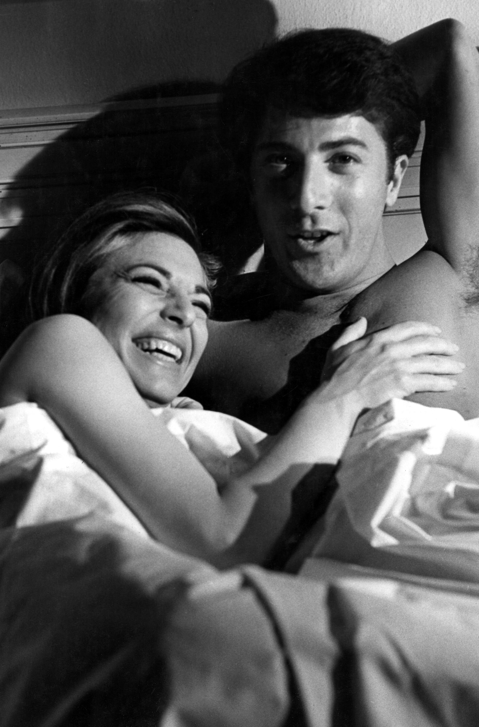 Bancroft and Hoffman laughing in bed