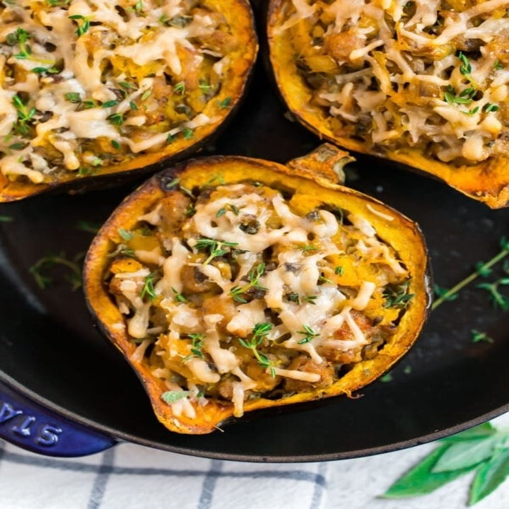 Three halves of acorn squash filled with sausage, apples, mushrooms, and cheese.