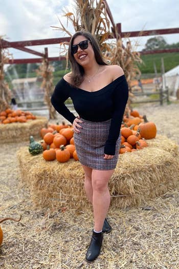 A reviewer wearing the skirt in gray and orange plaid