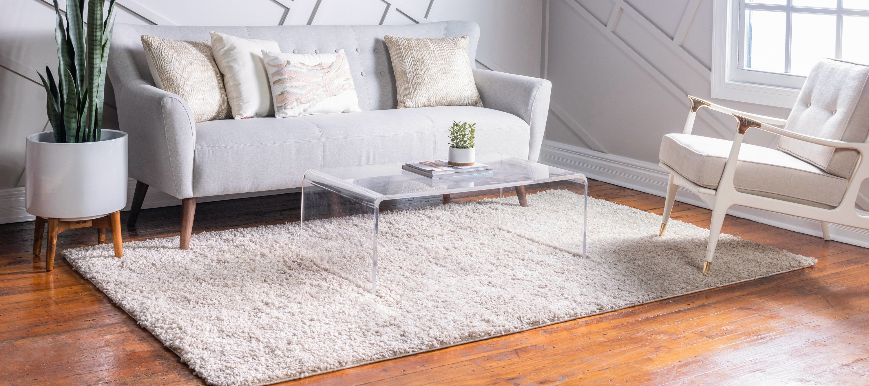 the shag rug in beige displayed in the living room underneath a glass table and couches 