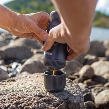 Hands pouring espresso into the lid that comes with the Nanospresso maker